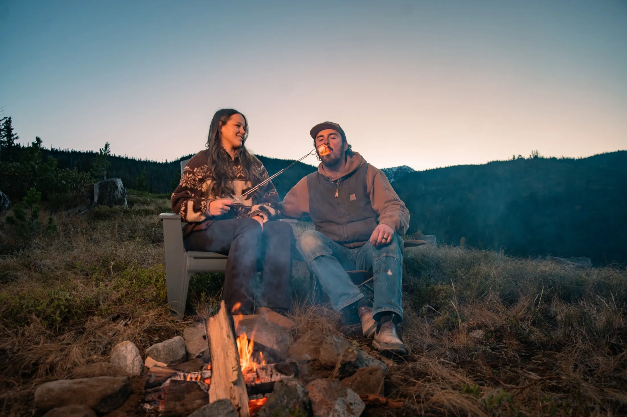 A couple by a crackling fire at dusk