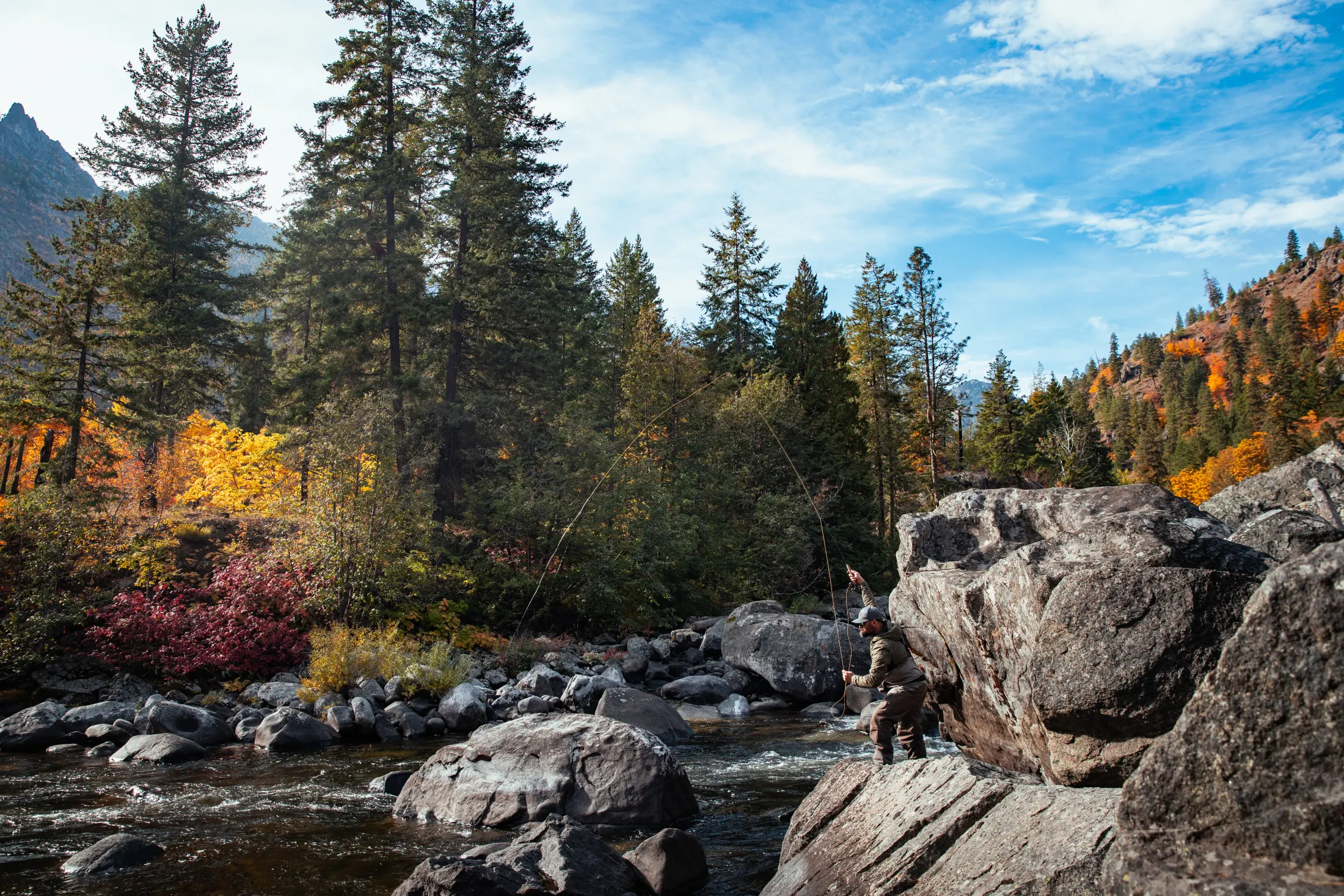 Angler casting from rocks in a mountain river