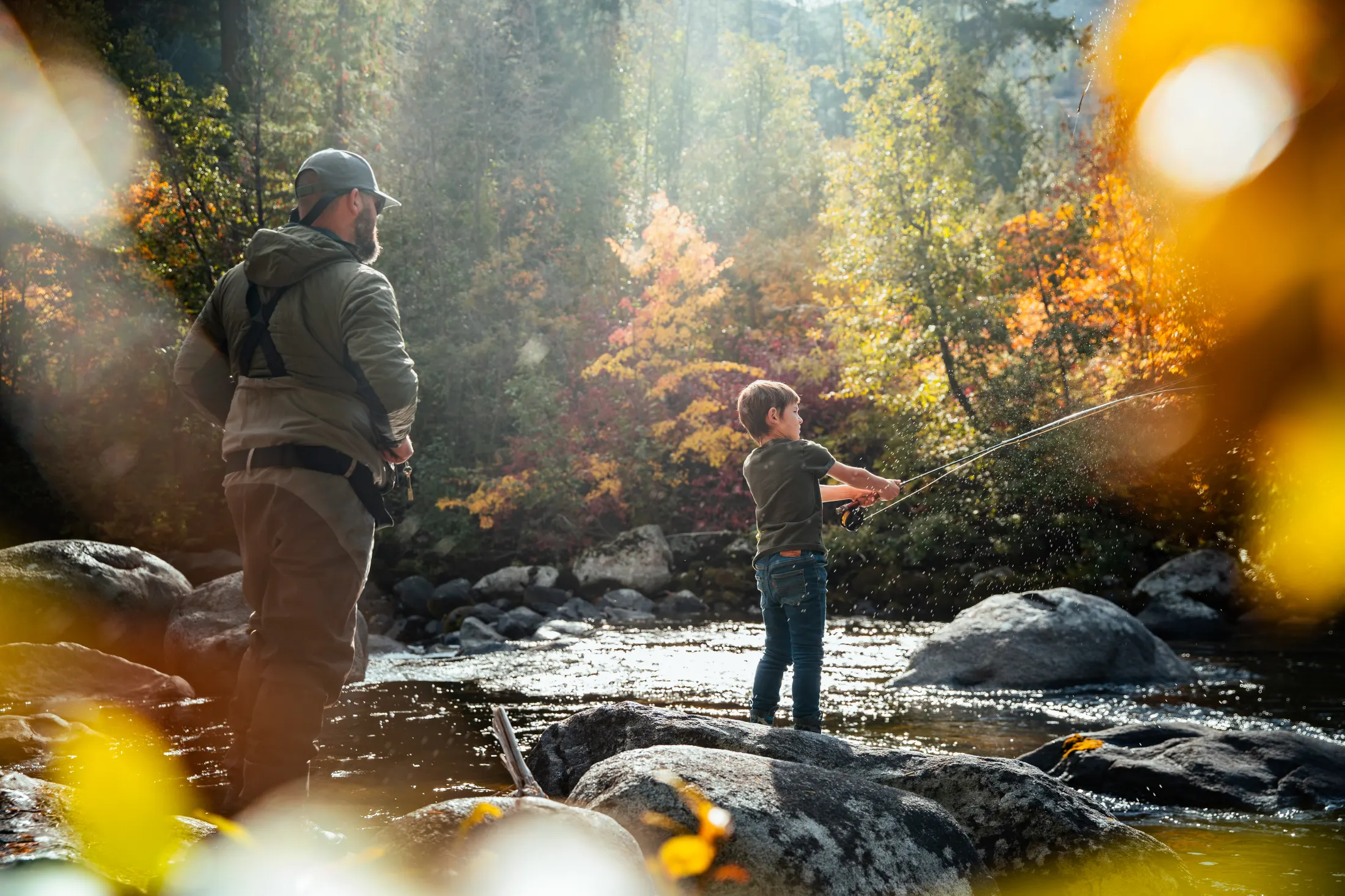 Angler casting in a backlit mountain stream