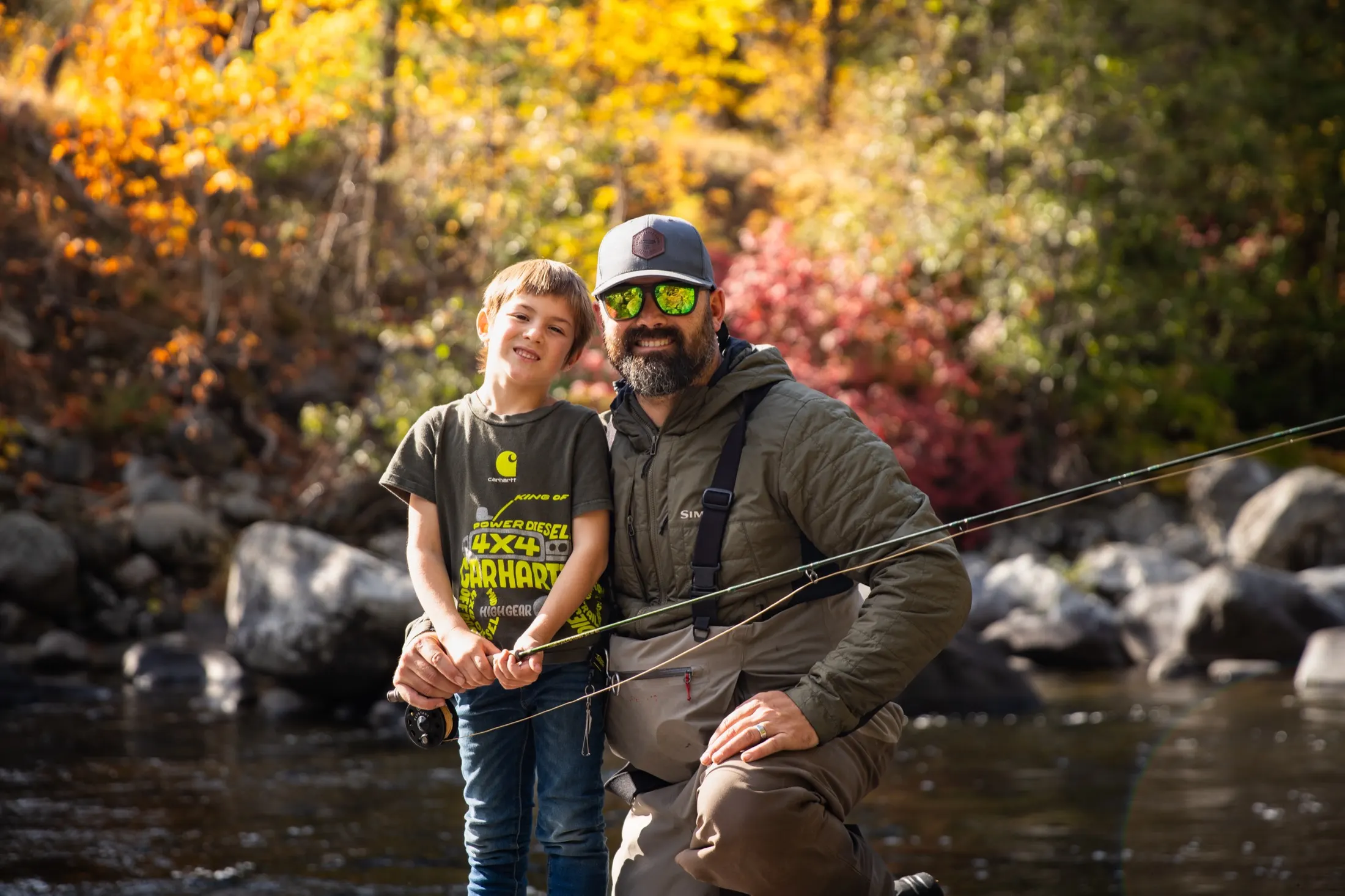 Father and son smiling beside the river