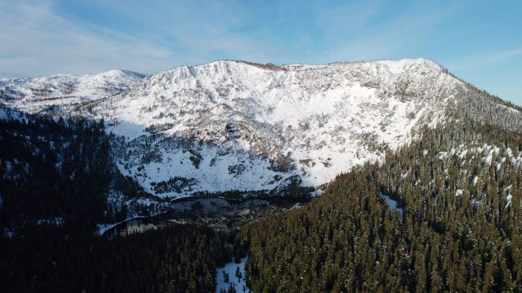Aerial view of the snowy ridge and forested slopes above the homesites