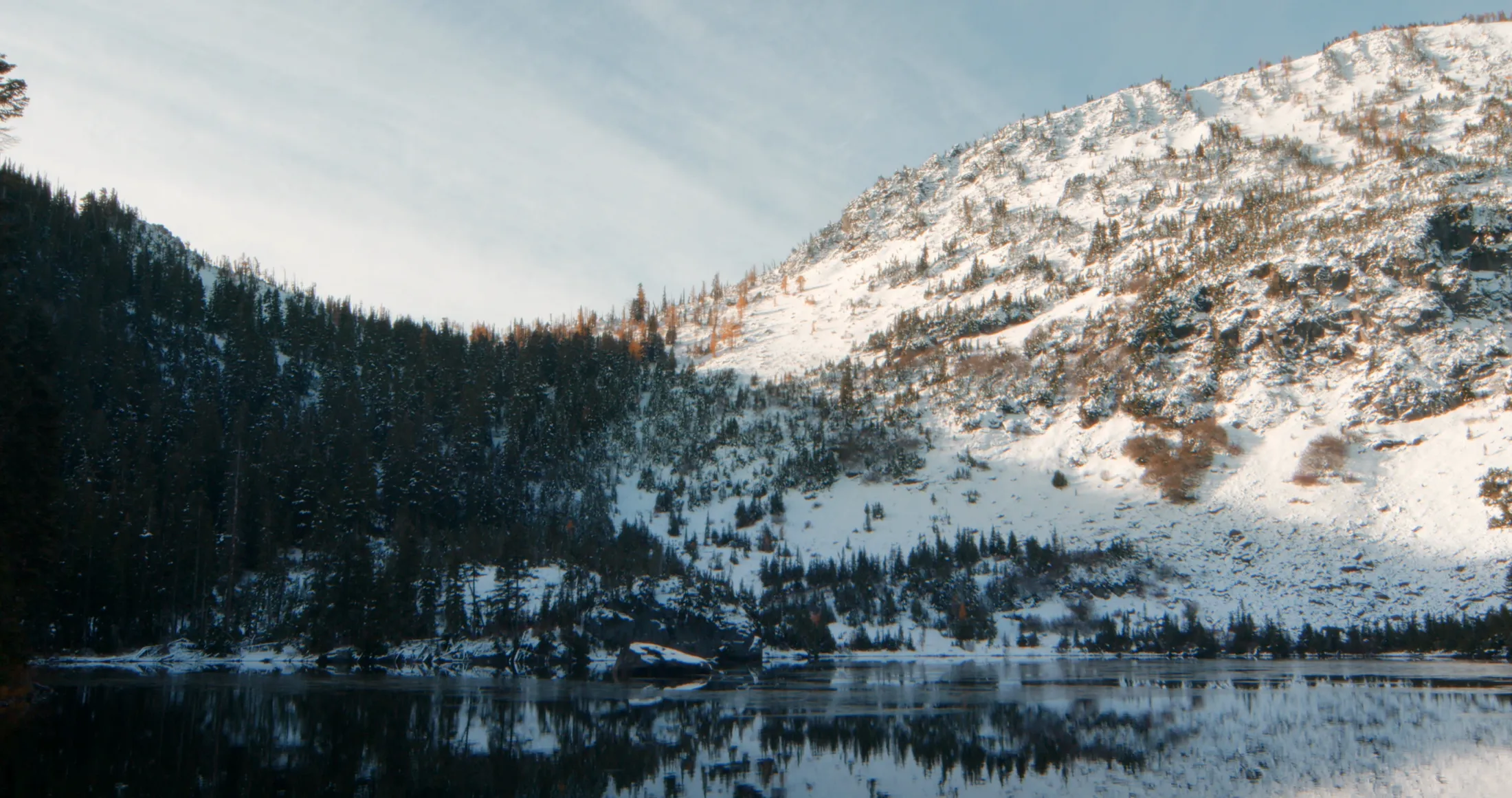 Snow-dusted cliffs reflected in an alpine lake