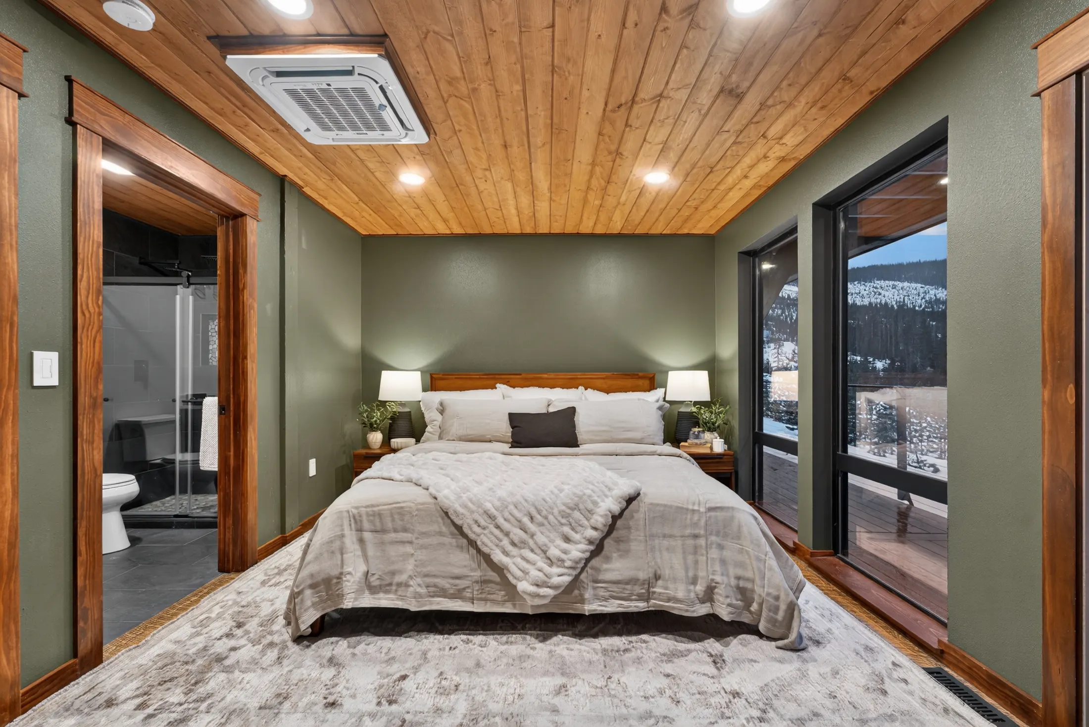 Primary bedroom with wood ceiling and forest view
