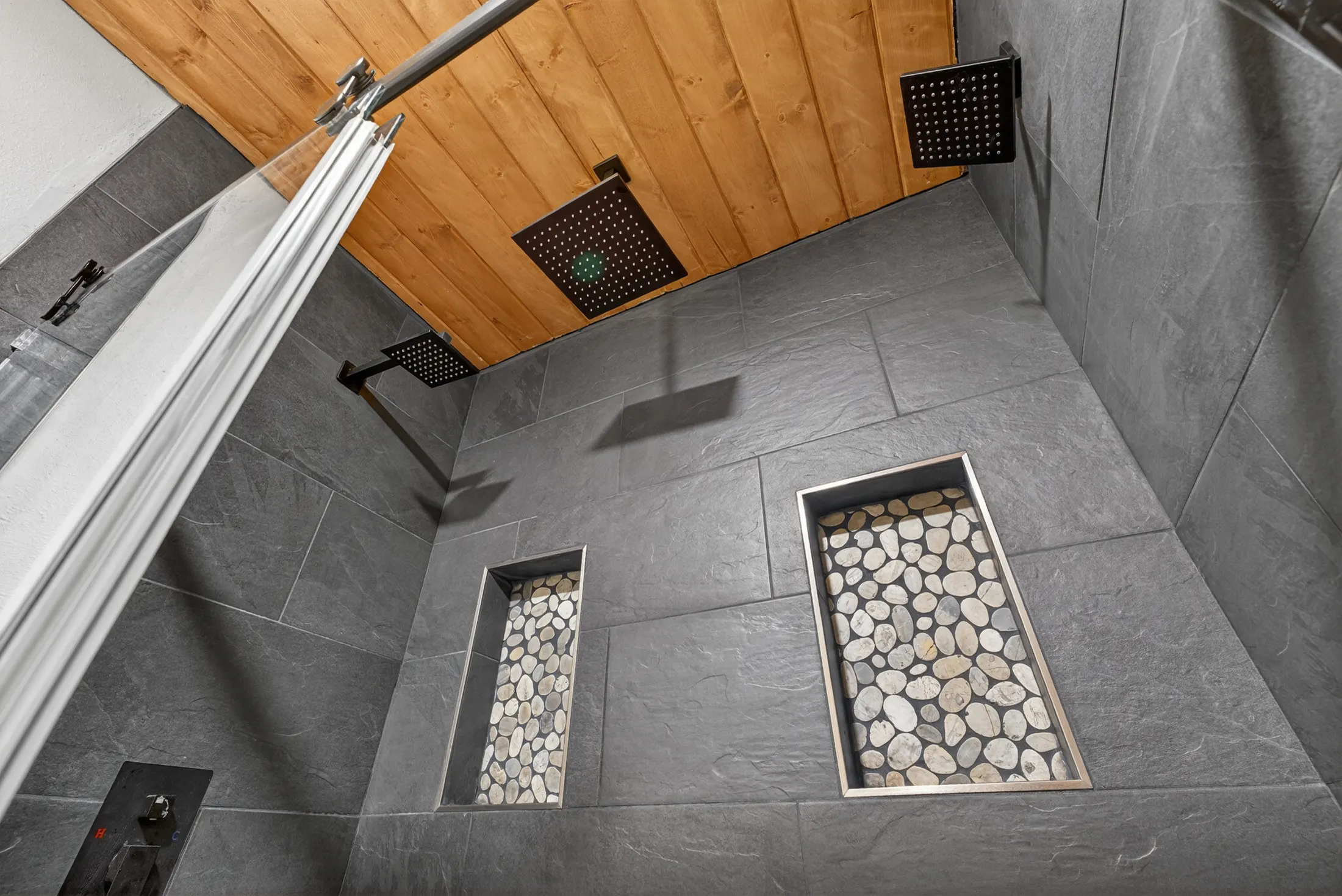 Stone-tiled shower under a wood ceiling