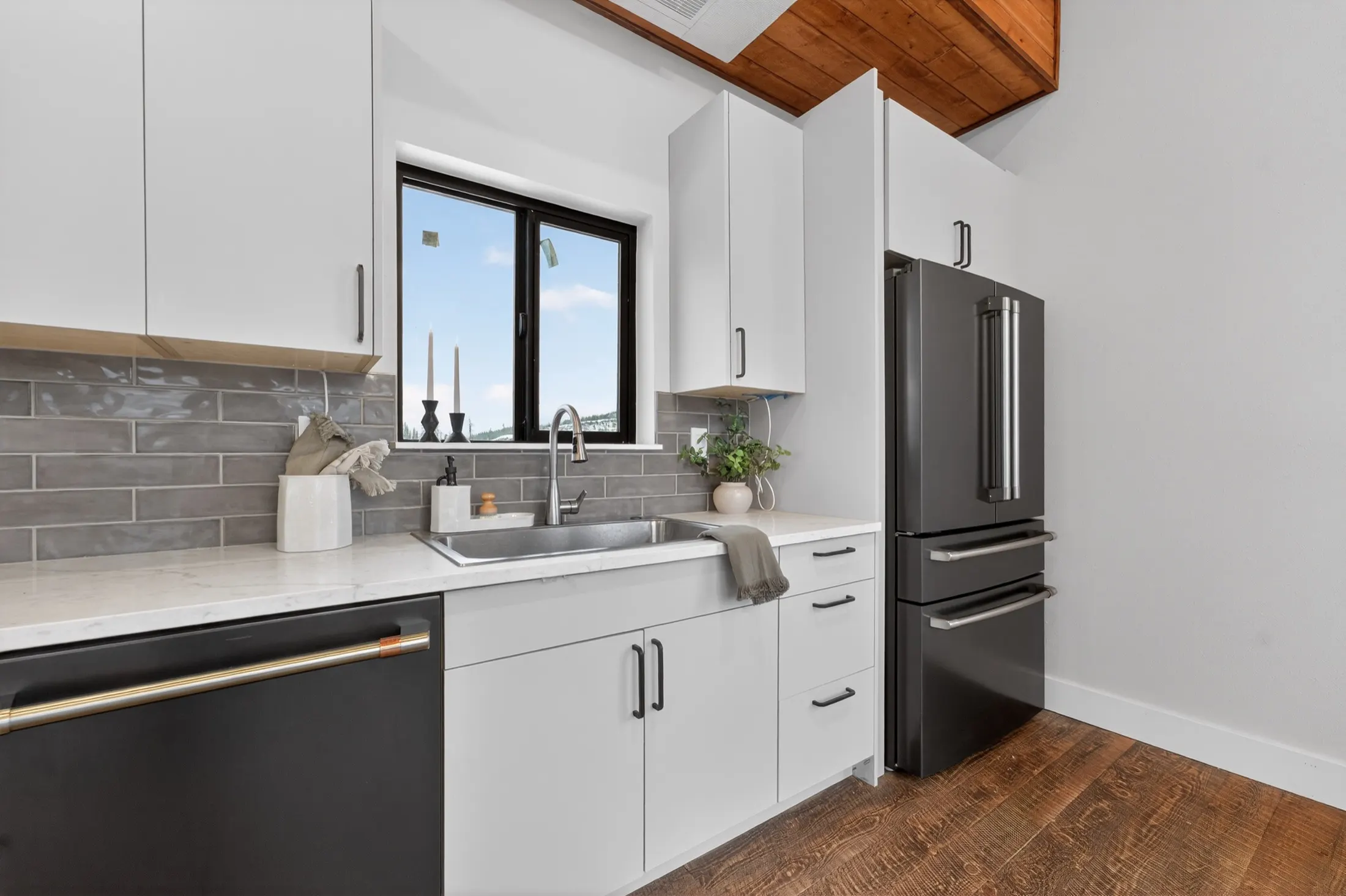 Kitchen with white cabinets and a window to the trees