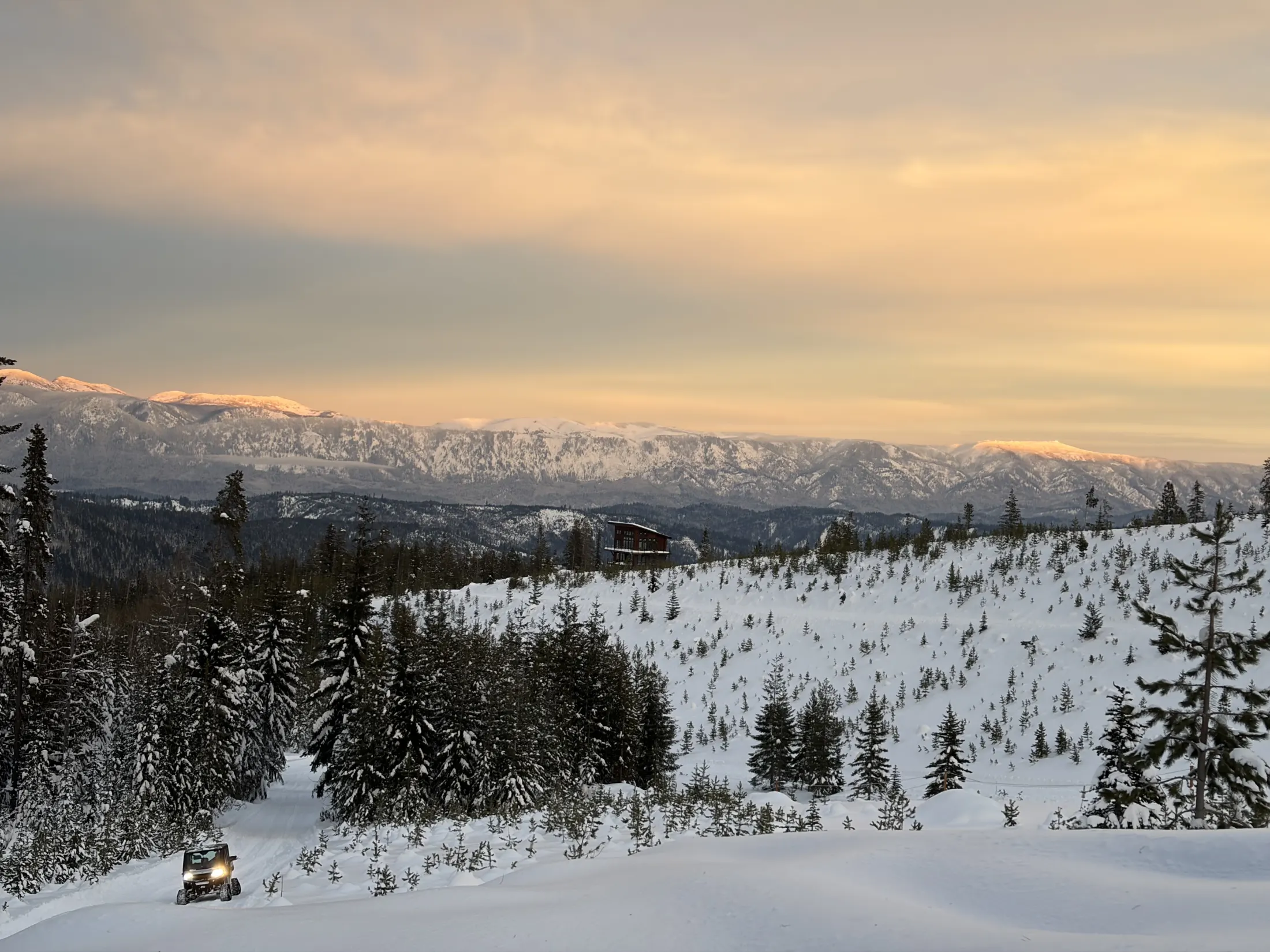 Sunset over a snowy bowl ringed by firs