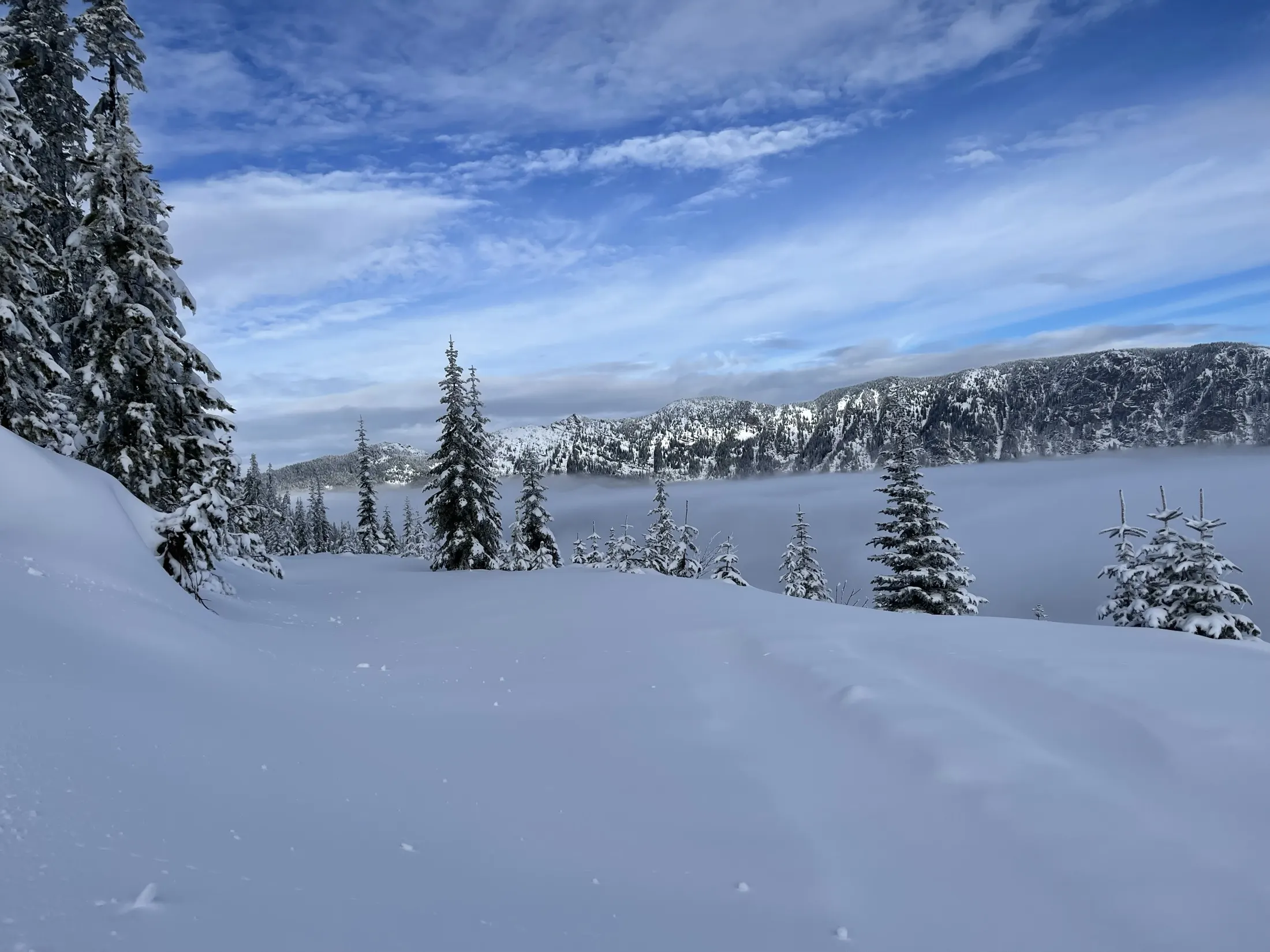 Snowy bench with clouds filling the valley