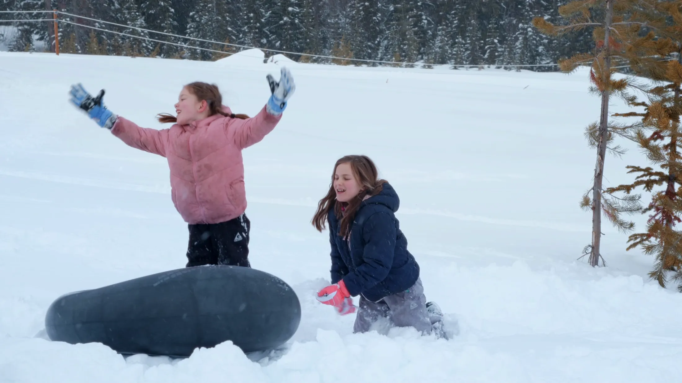 Two girls playing with a snow tube