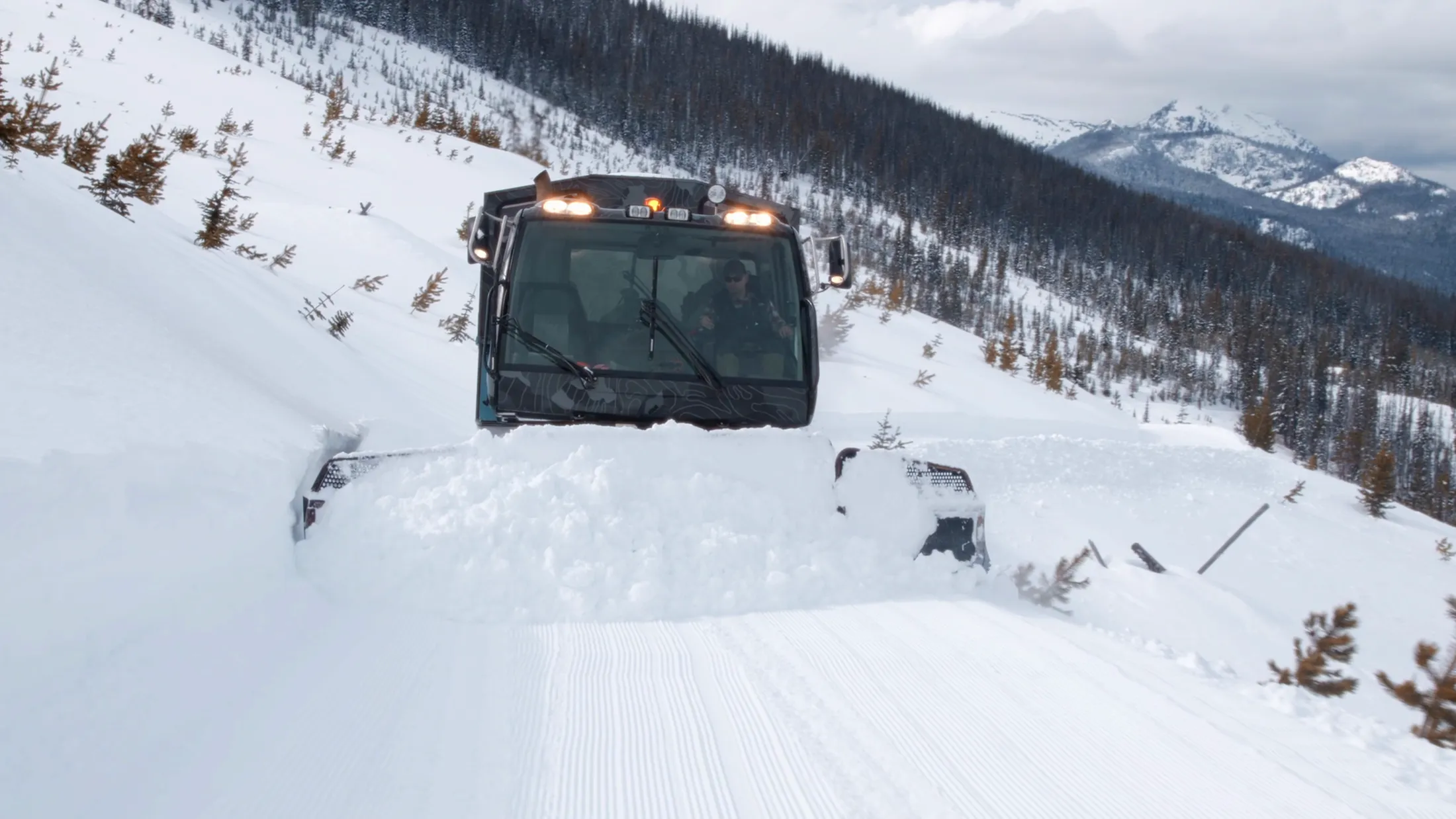 Snowcat cresting a snowy rise