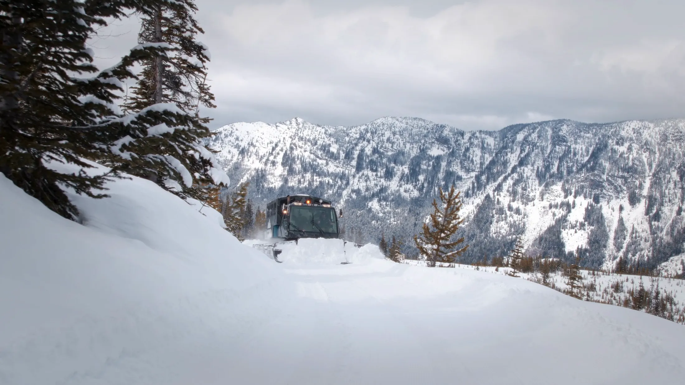 Snowcat on a ridge with mountains behind